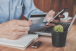 Man typing in credit card information into a mobile phone at desk