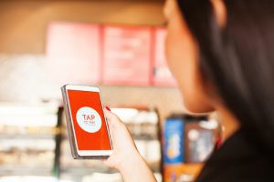 Woman holding mobile phone with "Tap" on the screen