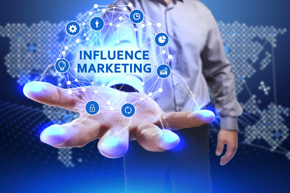 Business man holding a digitized web of elements with the words "Influencer Marketing"