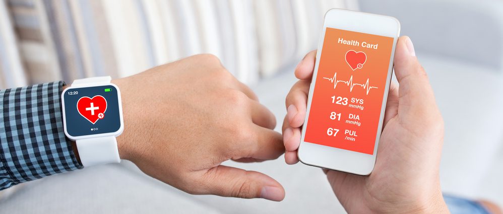 Patient wearing smart watch with vital metrics showing on smartphone screen