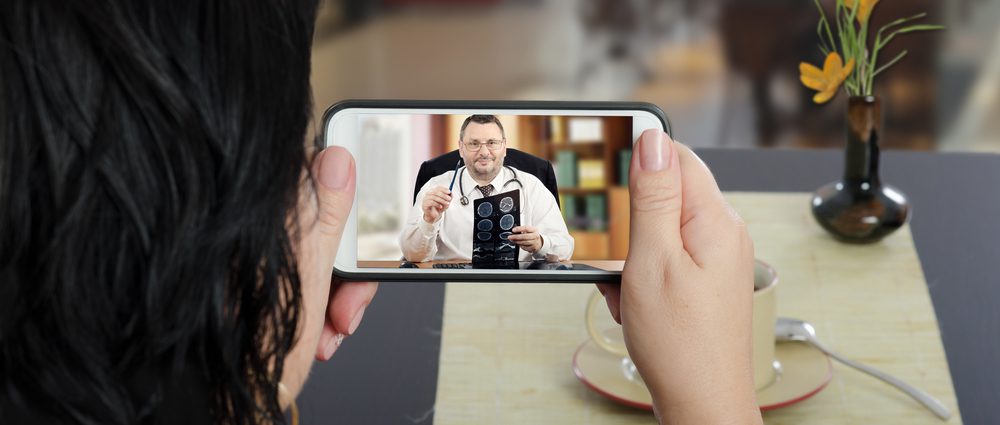 Woman and her doctor teleconferencing via a mobile device