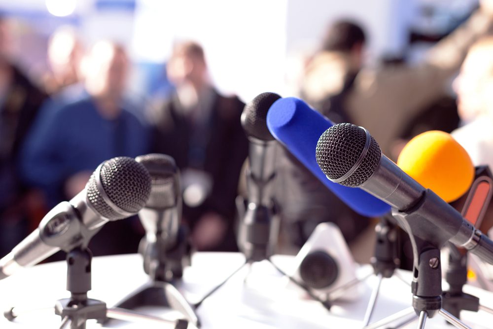 A handful of microphones set up for a press conference