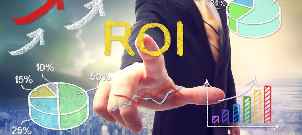 Man touching a drawing that says ROI and hard a chart pie next to it