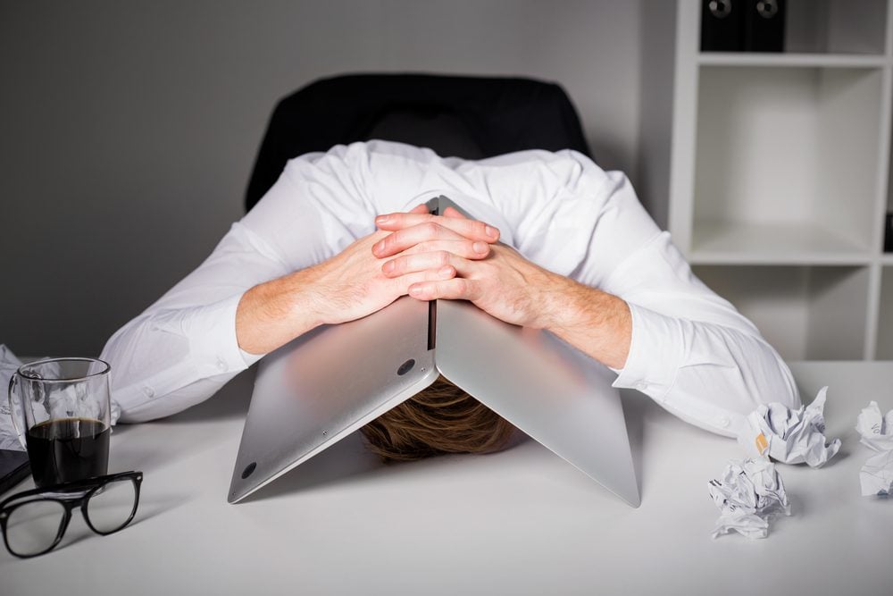 Stressed man holding his laptop over his head