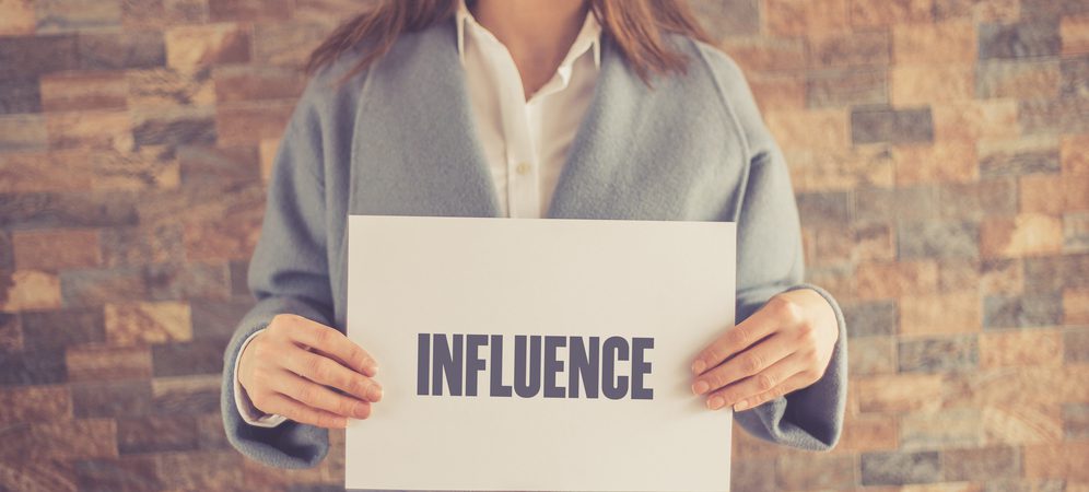 Woman holding a sign that reads Influence