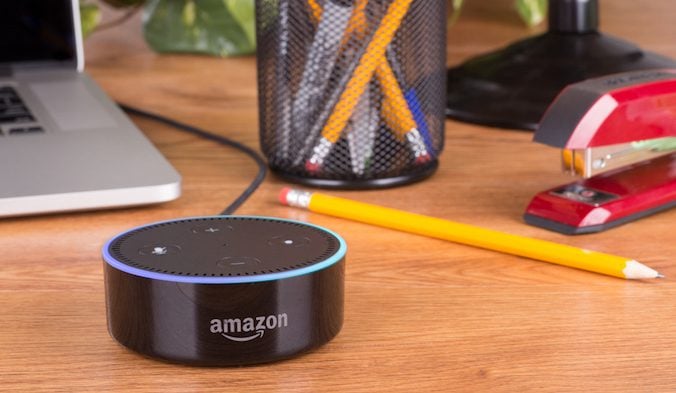 Amazon Alexa on a desk near business supplies and a laptop.