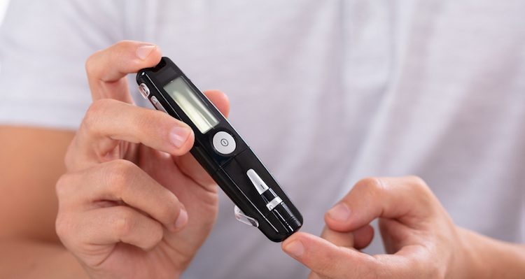 A person using a finger prick diabetes test