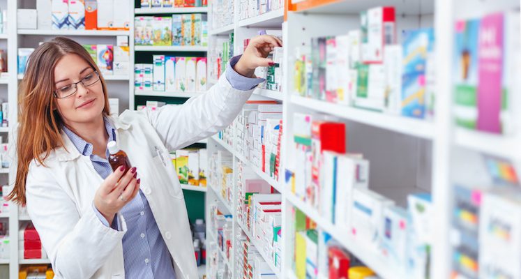 Female pharmacist examining bottles from pharmacy shelves