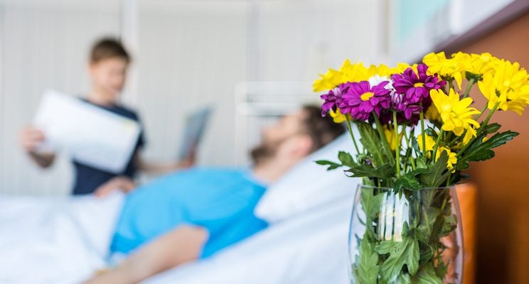 A male patient laying in hospital bed with flowers at his bedside