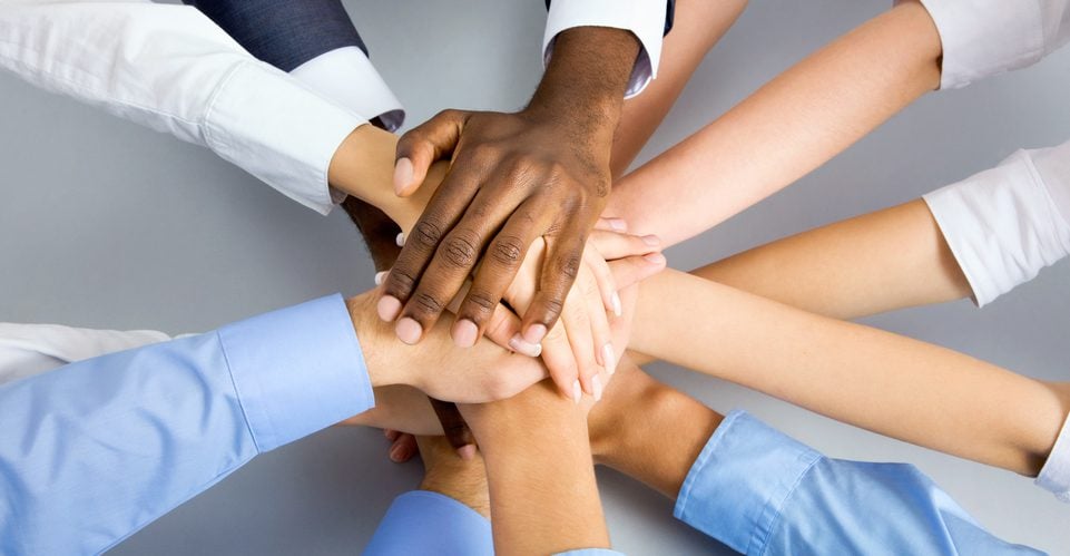 Hands together on top of each other in a display of teamwork.