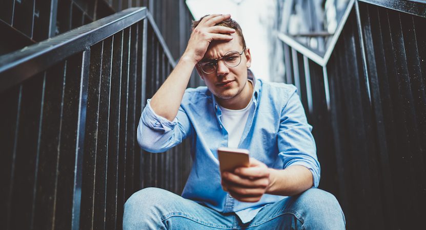 Man looking distressed at his phone.