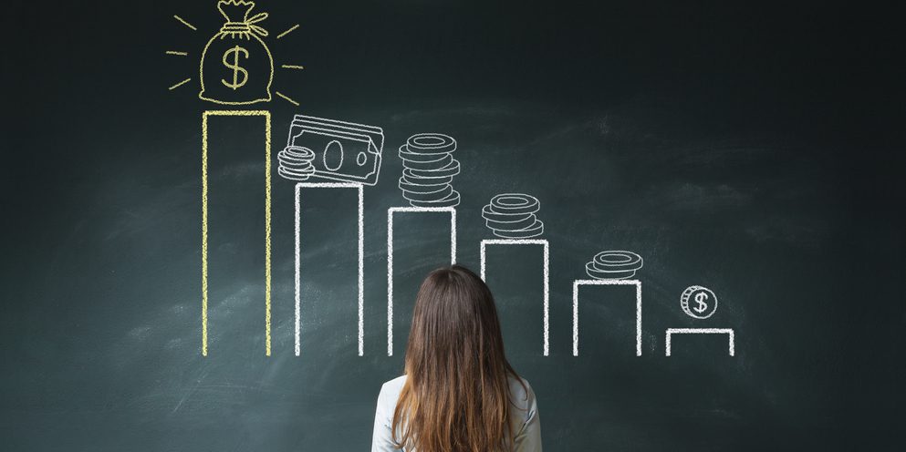 Woman staring at a bar graph with symbols of currency.