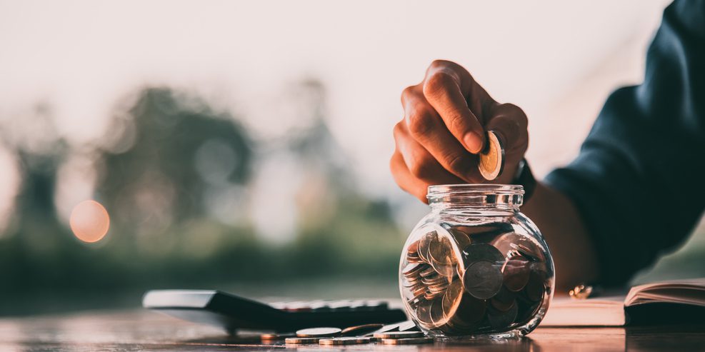 Man depositing a coin in a coin jar.