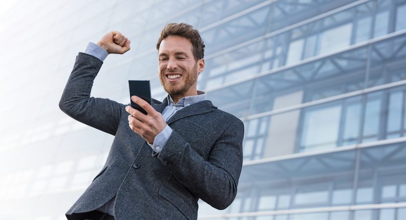 Man cheering while looking at his phone.