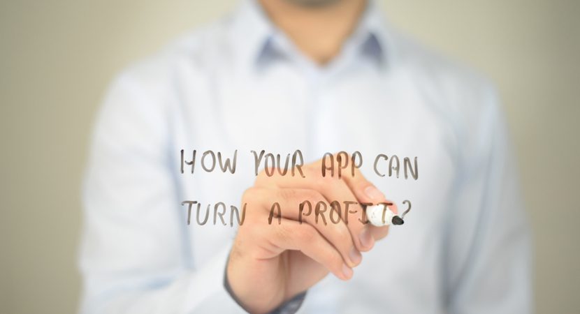 Man writing the words "How your app can turn a profit?" on a board.