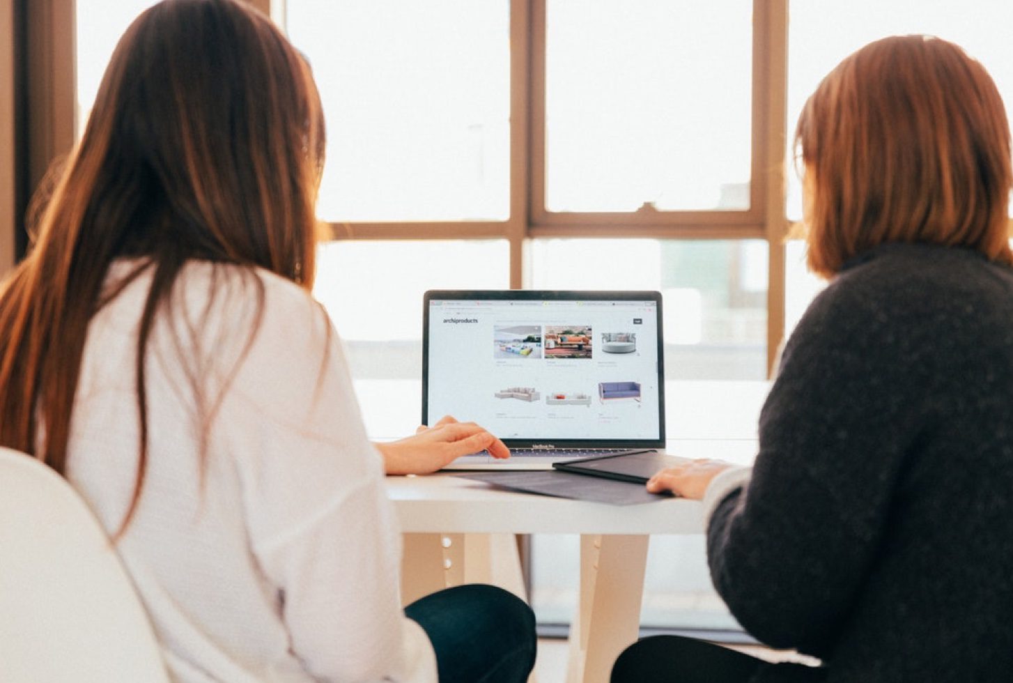 Two coworkers looking at a laptop.