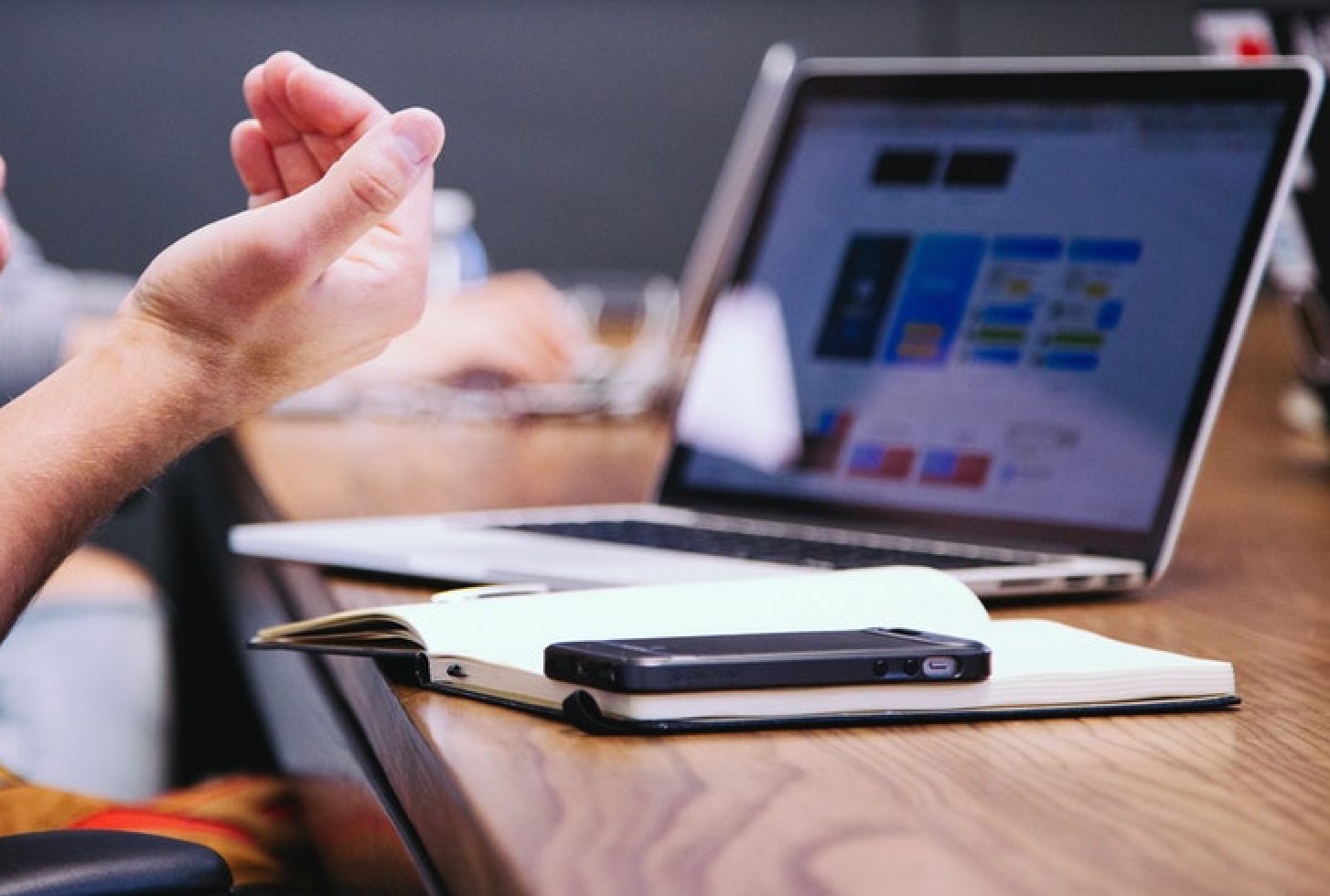 Person looking at a laptop with a pen and paper in front of them