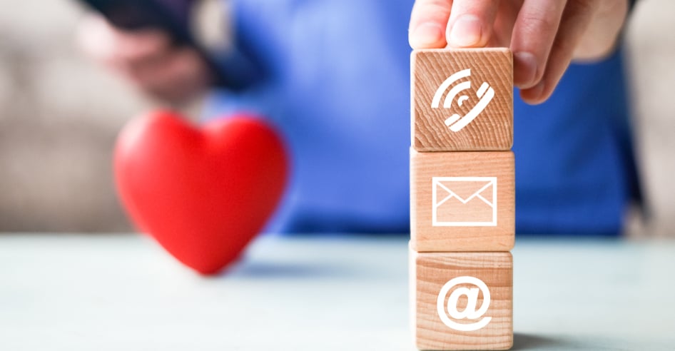 Wooden squares with contact contact icons painted on them and a red heart on the background