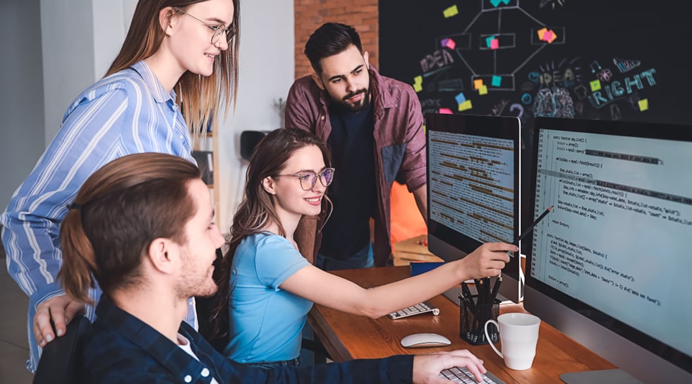 A team of software developers looking at two screens