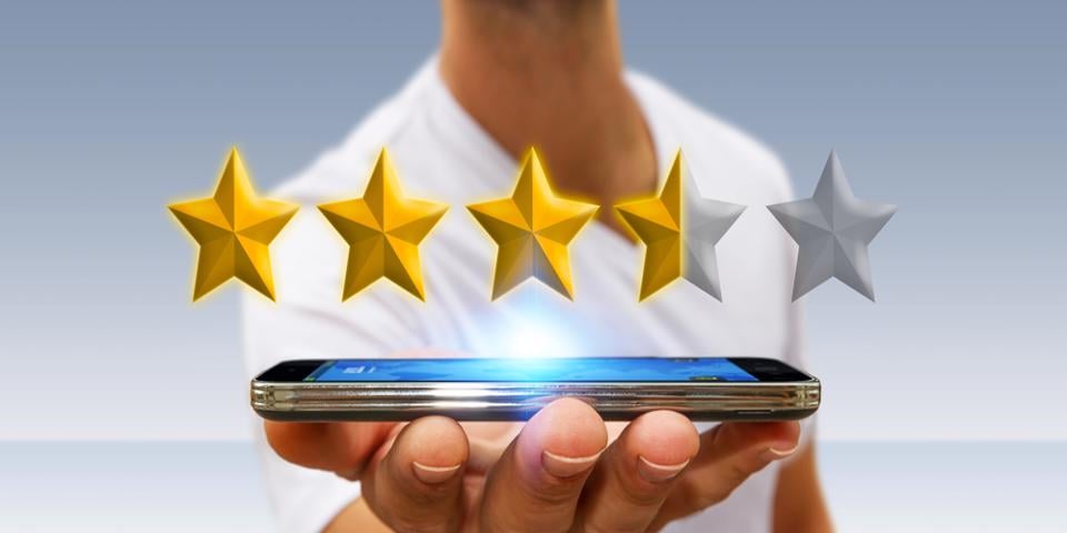 Person holding a mobile device in hand with customer reviews stars hovering over
