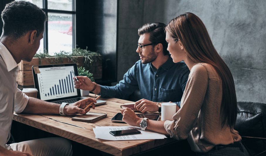 Marketing team of three looking at analytics on a  monitor