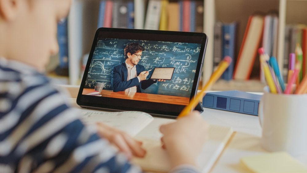 Smart Little Boy Uses Digital Tablet for Video Call with His Teacher. Screen Shows Online Lecture with Teacher Explaining Subject from a Classroom. E-Education Distance Learning, Homeschooling