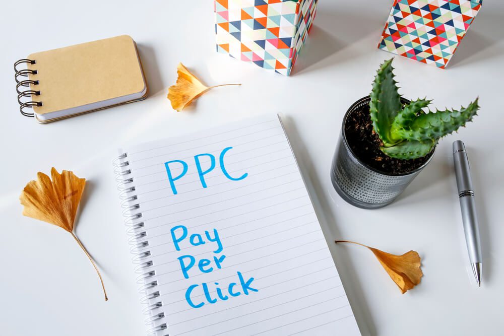 ppc advertising_PPC Pay Per Click written in notebook on white table