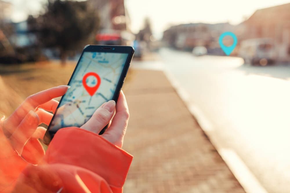 local search_Concept of Internet maps and navigation. Female hands hold smartphone with maps app, and marked location icon, red and blue destination icon