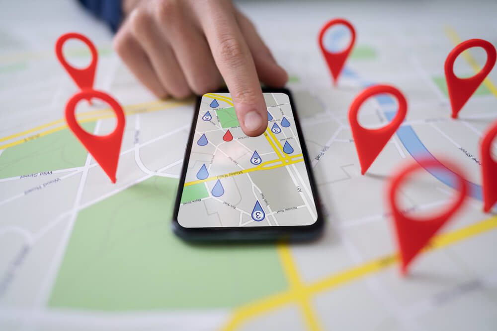 local search_Person Using Map With Red Location Markers On Mobile Phone