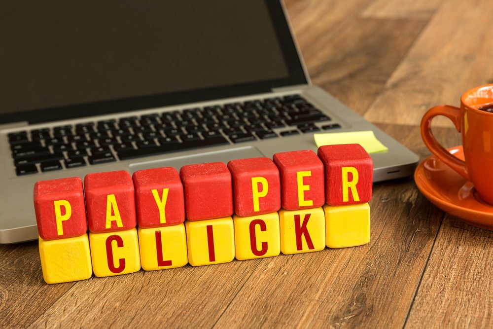 pay per click_Pay Per Click written on a wooden cube in front of a laptop