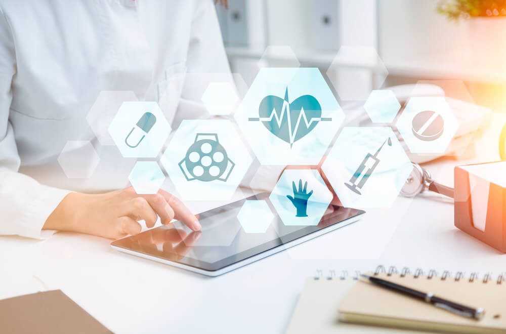 medical search_Doctor sitting at table and working with tablet. Medical icons in hexagonals in front. Only hands seen. Concept of medical help.