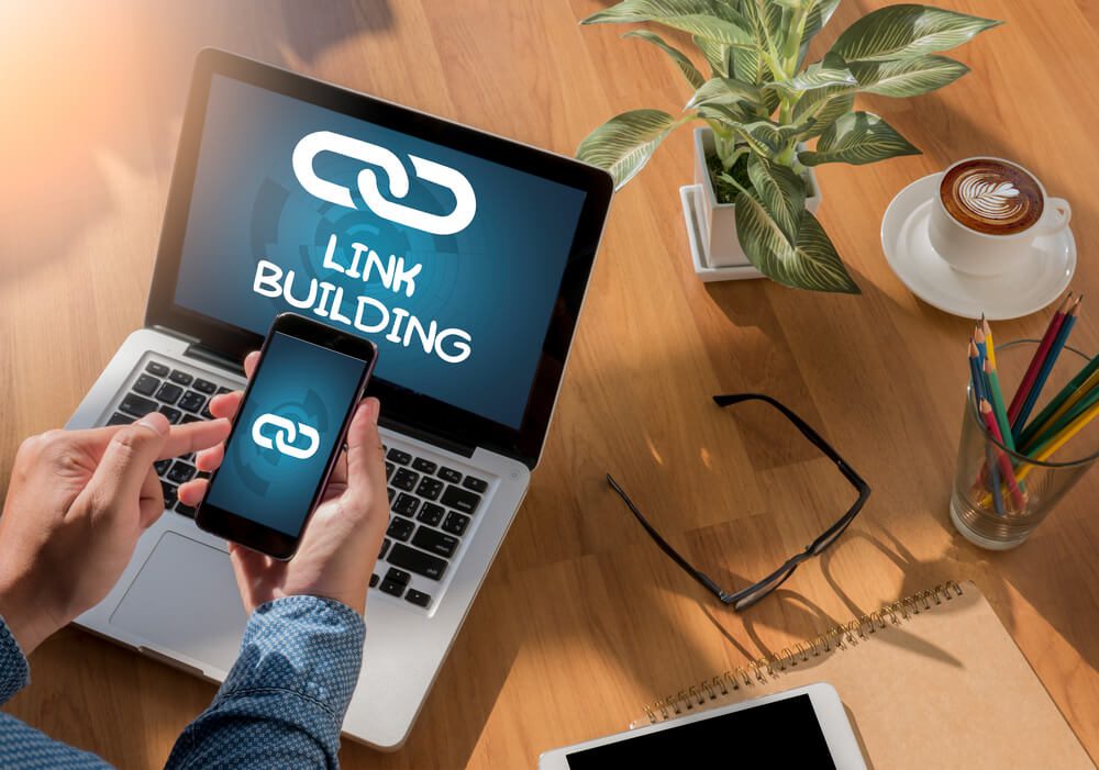 link building_LINK BUILDING Freelance desktop with accessories and distance work tools, blank screen laptop computer and phone, sunglasses, coffee