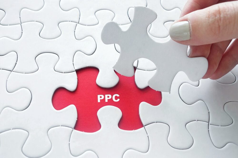 ppc consulting_Close up of girl's hand placing the last jigsaw puzzle piece with word PPC ( Pay Per Click )