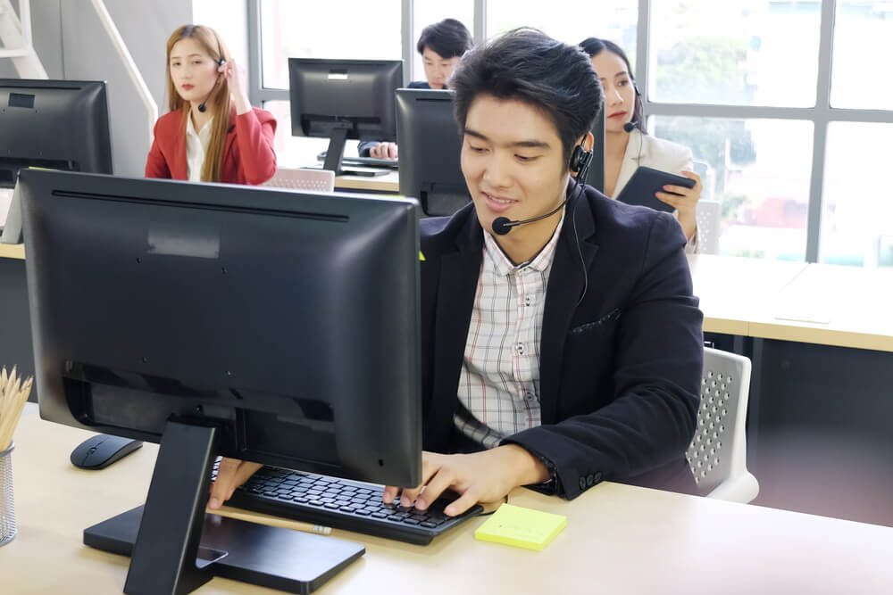 technical assistance_Smiling Businessman Call Center and technical Support staff or receptionist phone operator survice with headset and computer. Asian customer support team.