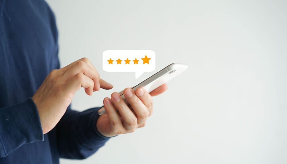 reviews_close up on customer man hand pressing on smartphone screen with gold five star rating feedback icon and press level excellent rank for giving best score point to review the service , business concept