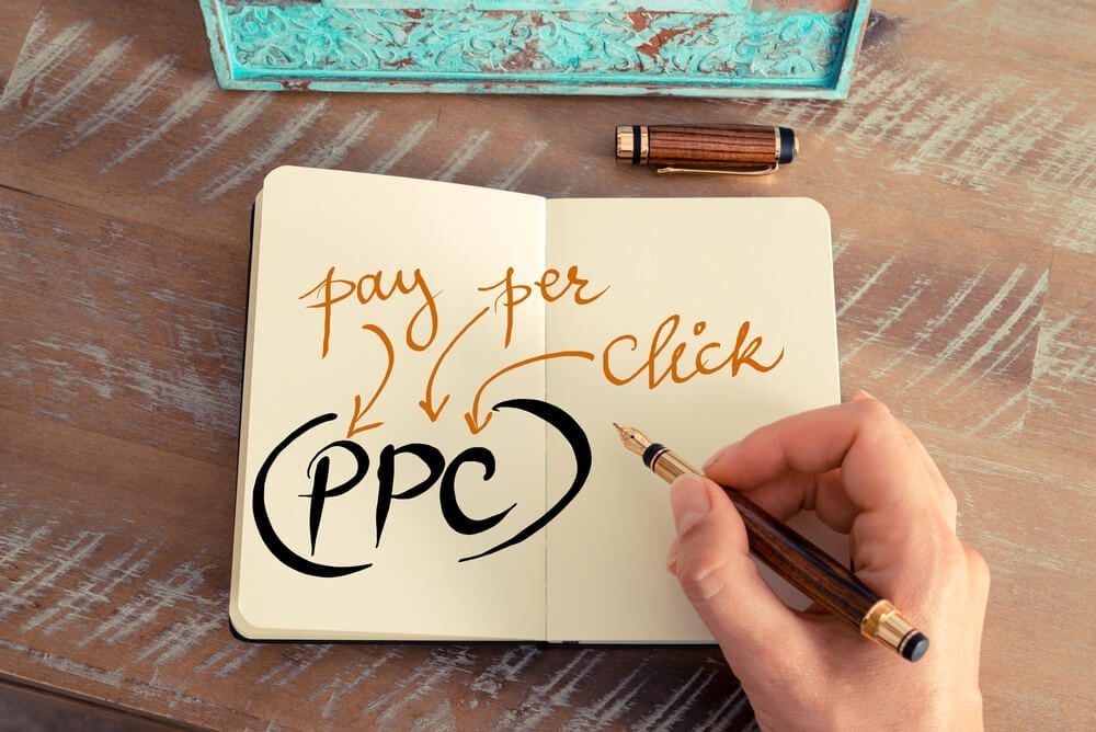 pay per click_Retro effect and toned image of a woman hand writing a note with a fountain pen on a notebook. Handwritten Business Acronym PPC PAY PER CLICK, motivation concept