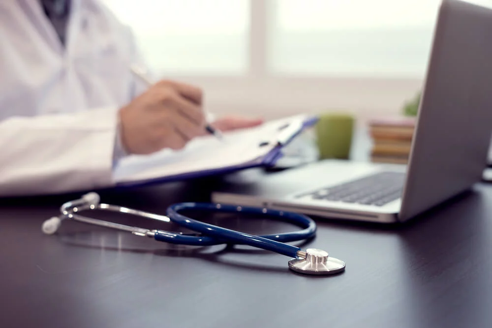 medical practices_Stethoscope with clipboard and Laptop on desk,Doctor working in hospital writing a prescription, Healthcare and medical concept,test results in background,vintage color,selective focus