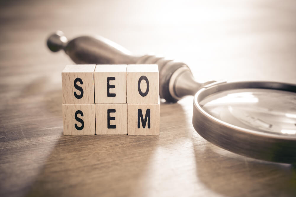 seo and sem_Old Magnifying Glass Lying Next to SEO And SEM Blocks In Monochrome Colors - Search Engine Optimization And Marketing Concept