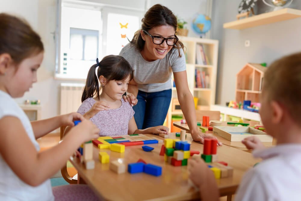 daycare center_Preschool teacher with children playing with colorful wooden didactic toys at kindergarten