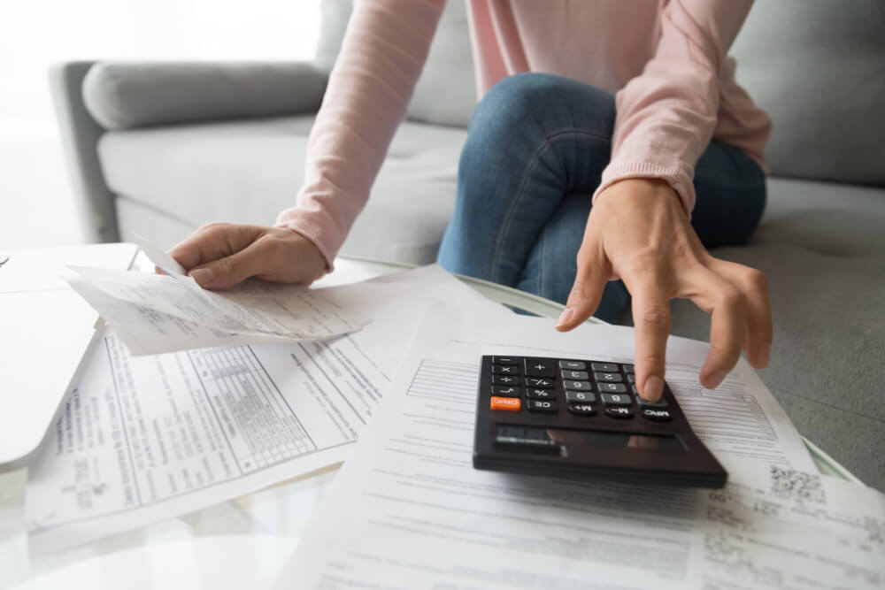 billing_Woman renter holding paper bills using calculator for business financial accounting calculate money bank loan rent payments manage expenses finances taxes doing paperwork concept, close up view