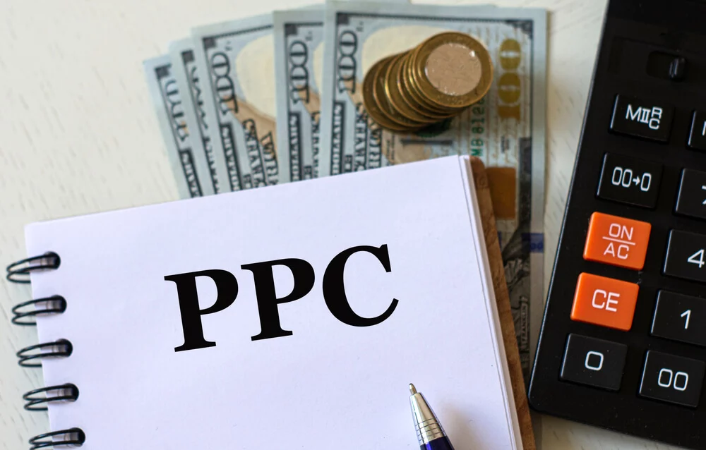 ppc budget_PPC (Pay per Click) - words in a notebook against the background of calculitar and banknotes. Business and finance concept.