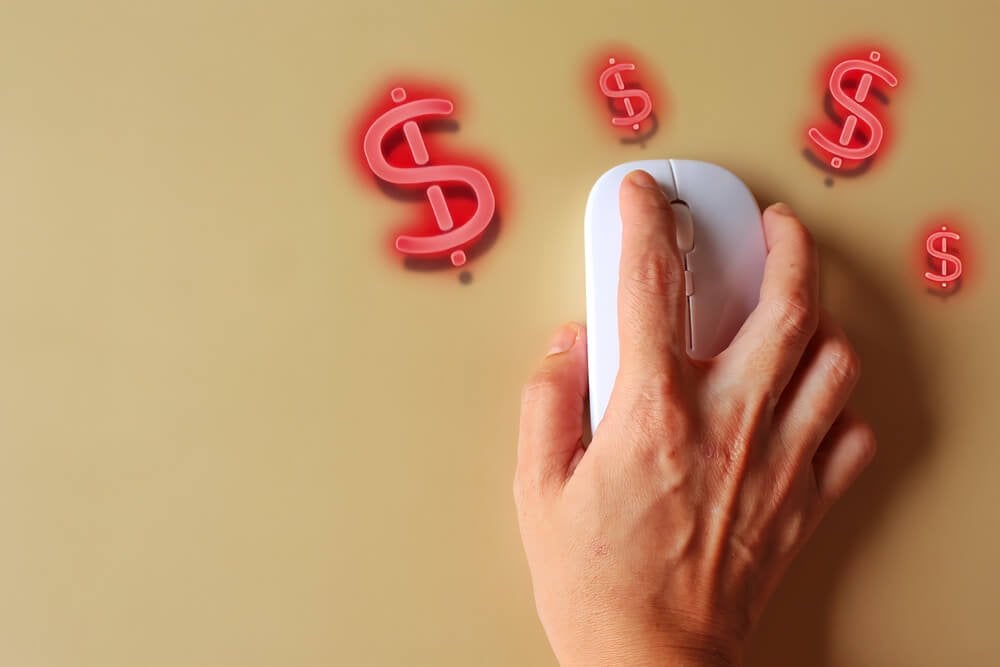 Finger clicking wireless mouse with glowing dollar sign, representing online shopping.