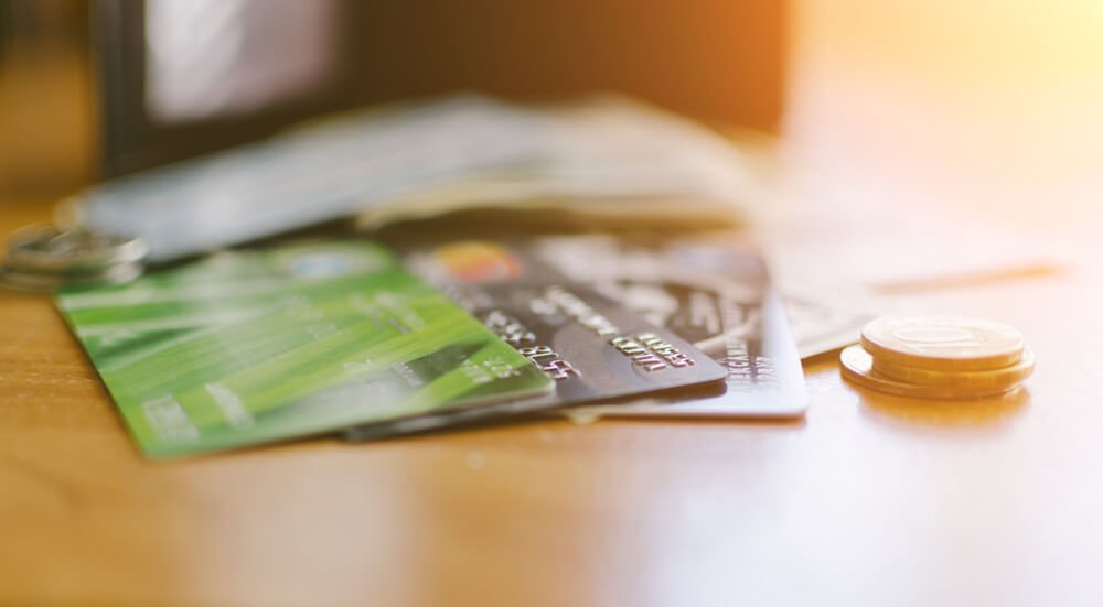 fees and charges_Money, credit bank cards and coins on the home wood table with selective focus and soft sun light