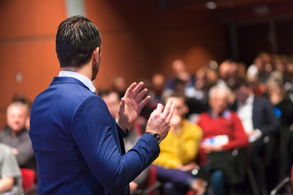 public speaker_Public speaker giving talk at Business Event.