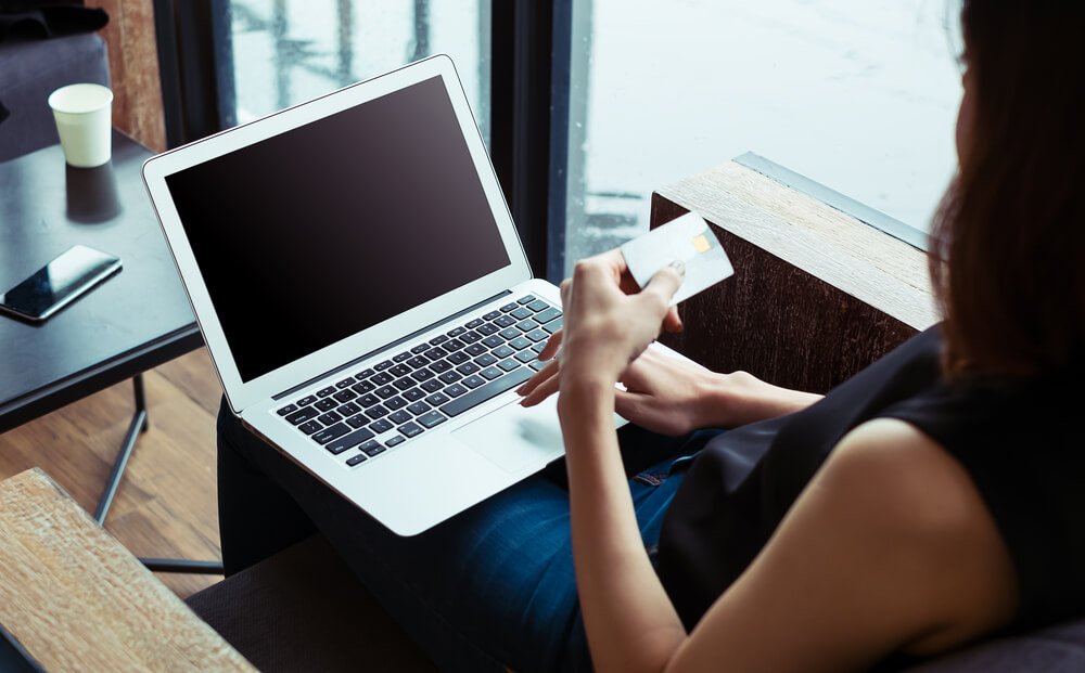 ppc billing_Woman's hands holding a credit card and using laptop for online shopping.