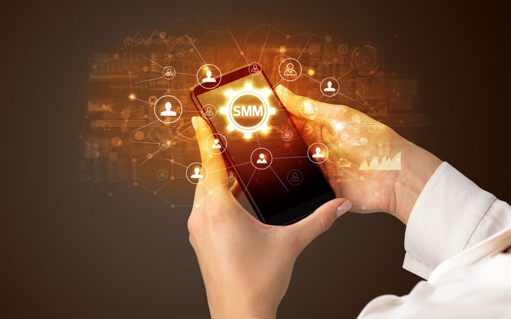 SMM_Female hand holding smartphone with SMM abbreviation, modern technology concept