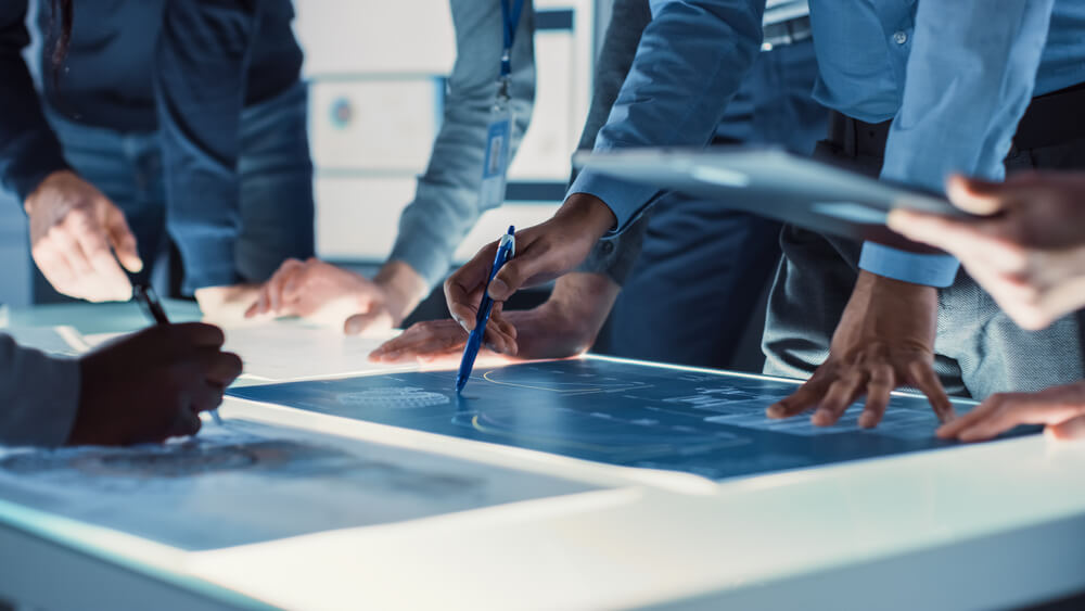 agency_Engineer, Scientists and Developers Gathered Around Illuminated Conference Table in Technology Research Center, Talking, Finding Solution and Analysing Industrial Engine Design. Close-up Hands Shot