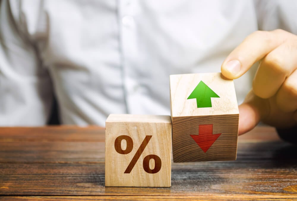 low ranking_Businessman holds wooden blocks with percent and up or down arrow. Mortgage and loan rates. Interest rate, stocks, ranking. Business and finance concept.
