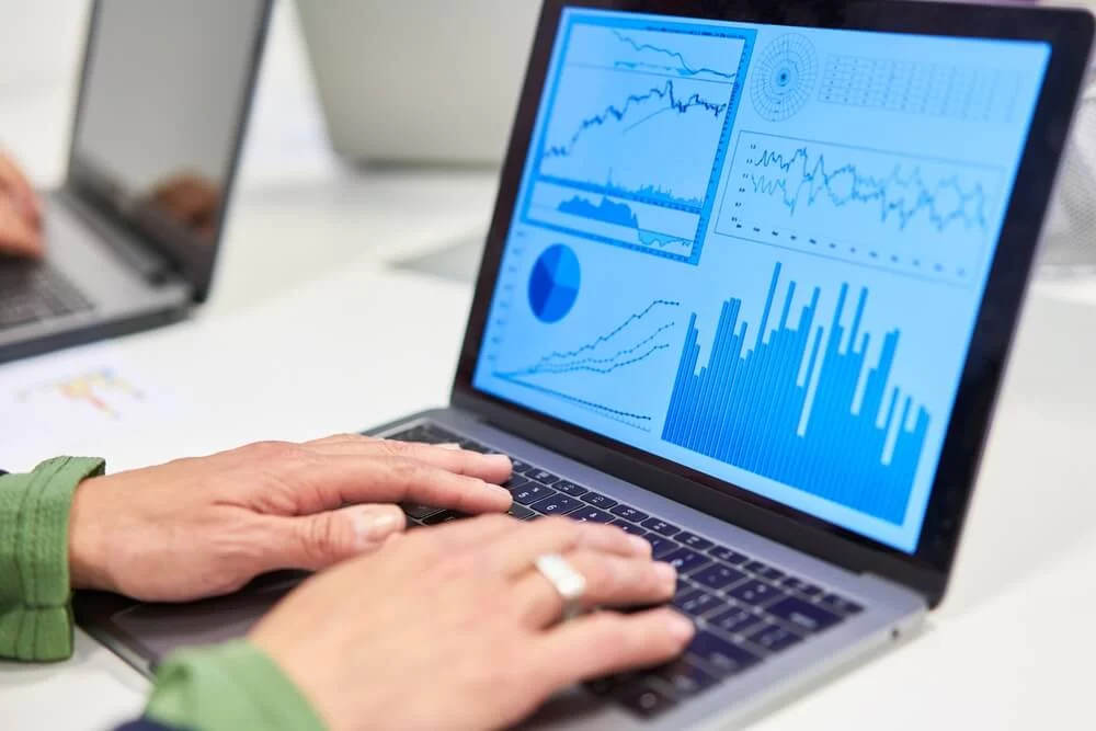 seo forecasting_Hands writing on laptop computer with graphs and charts in financial analysis