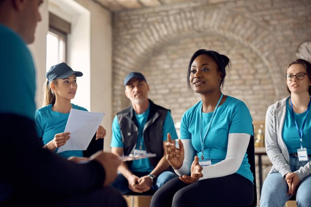 non profit_Team of volunteers having a meeting while working at donation center. Focus is on African American coordinator.